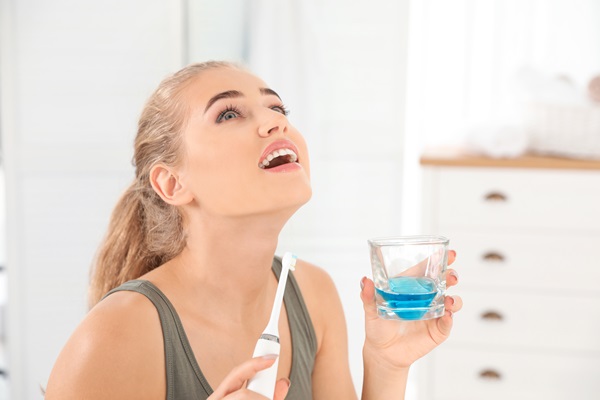 Woman Rinsing Mouth With Mouthwash In Bathroom. Teeth Care